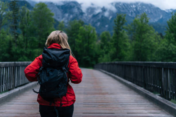 istock Young woman backpacker hikes across bridge in the forest 1266491876
