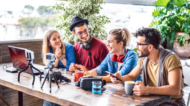 istock Digital native friends sharing feed on streaming platform with phone and web cam - Content marketing concept with millenial workers having fun vlogging live video on social media space - Bright filter 1266493476