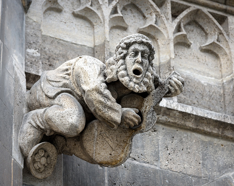 Gargoyle on wall of Rathaus or Town Hall on Marienplatz Square, Munich, Bavaria, Germany. This building is landmark of Munich. Gothic statue like medieval guitar player close-up in Munich city center