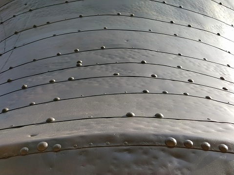 Structure of old metal with rivets. The surface of a space dish, UFO or submarine. Industrial metal construction.