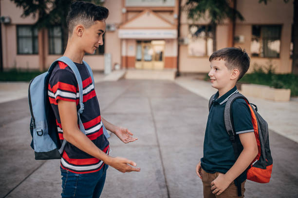 istock Young schoolboys talking in schoolyard 1266504198