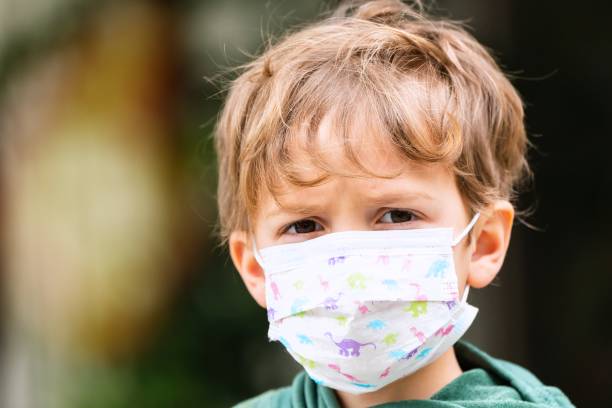 istock Pensive annoyed Little child boy at school looking at the camera using a protective face mask 1266505910
