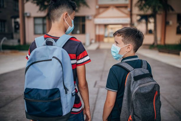 istock Boys with protective face masks going to school 1266505920