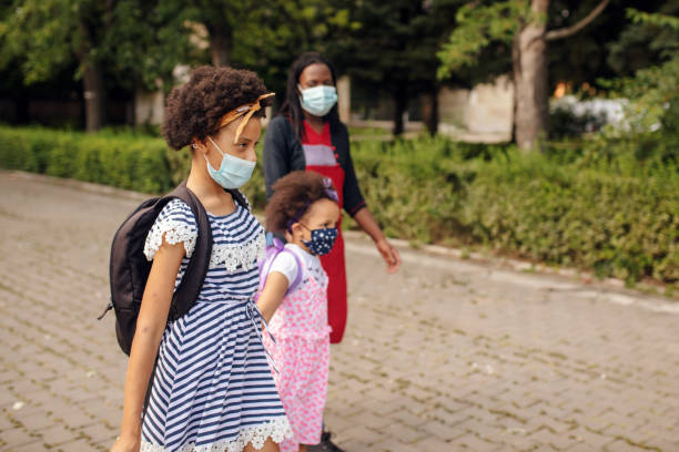 istock Mother with elementary school students going to school with face masks 1266512191
