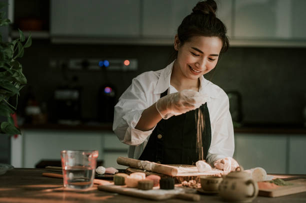 una mujer hermosa china asiática haciendo chino tradicional de mediados de otoño piel de nieve mooncake en su cocina - home baking fotografías e imágenes de stock