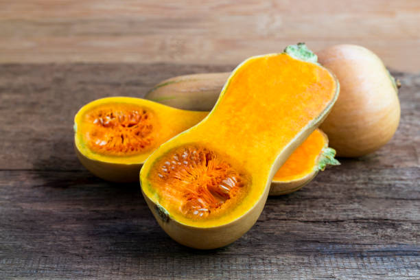 istock Butternut squash whole and sliced on a wooden table. Butternut is a bell-shape fruit with sweet orange-yellow flesh. 1266531326