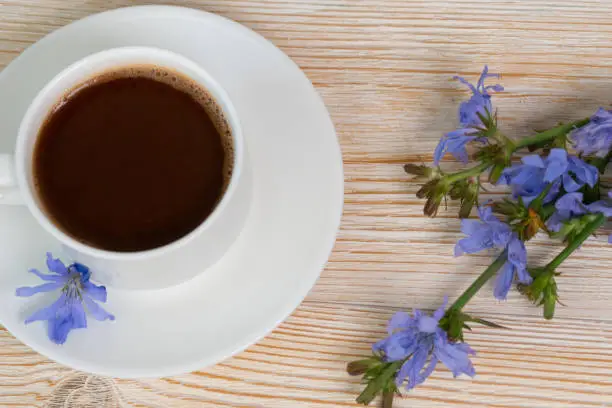 hot chicory drink with blue flowers on wooden table