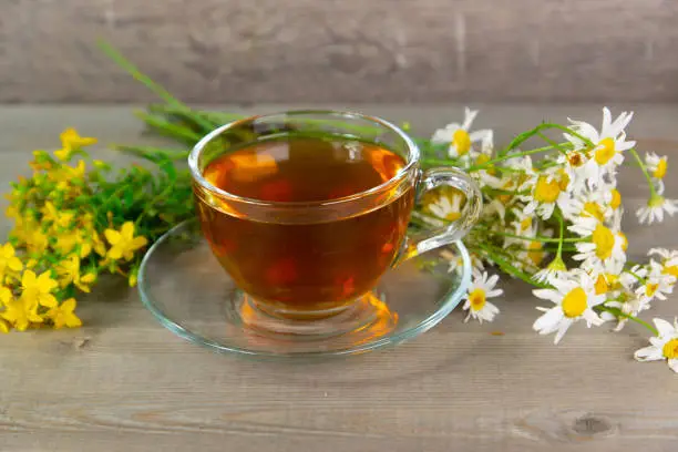 tutsan and camomile herbal tea in transparent glass cup