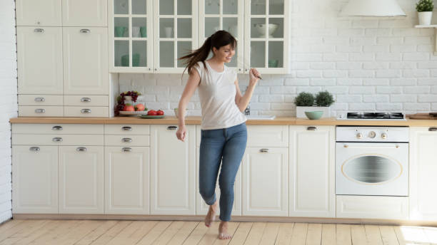 istock Happy joyful young woman dancing and singing at kitchen 1266551918