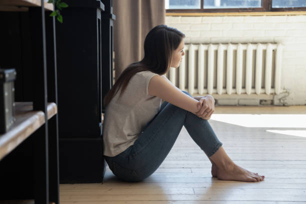 istock Thoughtful depressed young female sitting on floor hugging knees 1266551919