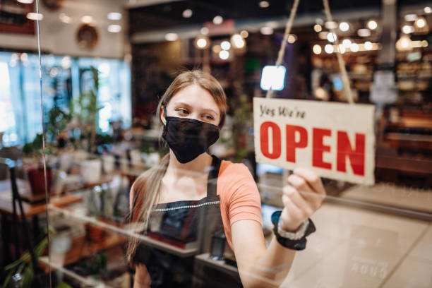 istock Waitress with face mask holding Open sign in cafe after coronavirus lockdown 1266552119