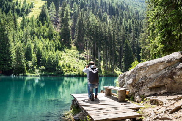 istock Photographer Man Taking Mountain Lake Photo 1266552946