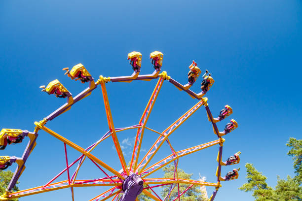 tour extrême en mouvement dans le parc d’attractions à la journée ensoleillée - ferris wheel wheel blurred motion amusement park photos et images de collection