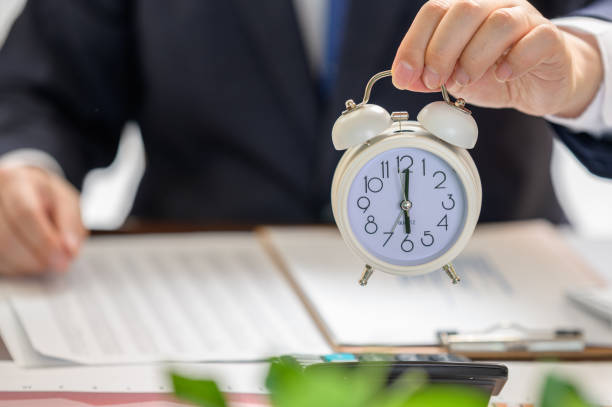 istock Businessman holding a white alarm clock. Work Time concept. 1266555861