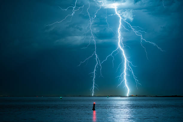 branched lightning bolts strike down near the coast - summer landscape flash imagens e fotografias de stock