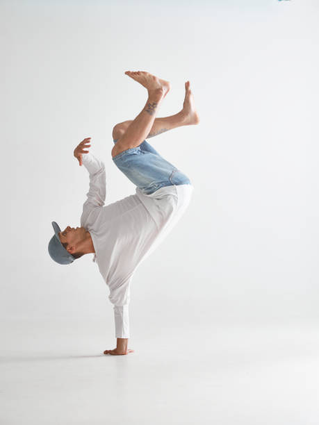 istock Young breakdancer stands on one arm dancing hip-hop isolated on white background. Break dance school poster 1266556513