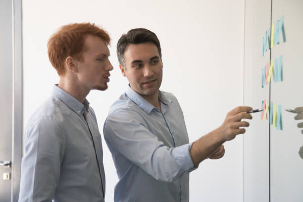 istock Colleagues discussing startup ideas, looking on sticky papers 1266558160
