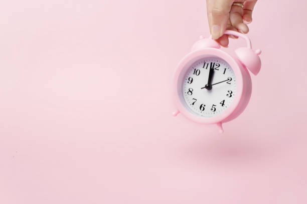 istock A hand holds alarm clock. A concept of the time and new technologies. Light pink background. 1266558262