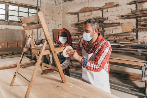 istock Couple Carpenter Workers Making a Chair in Their Workshop - COVID-19 1266561399