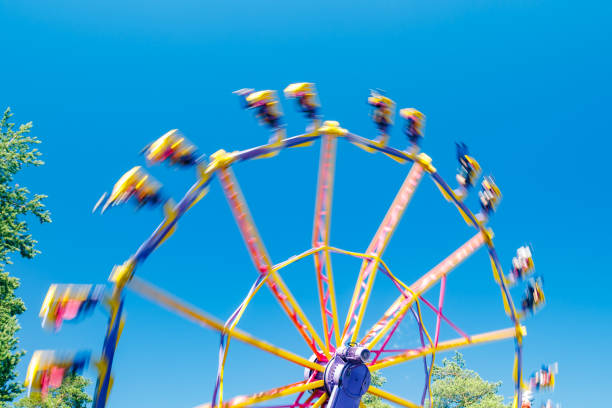 晴れた日に遊園地で動きの極端な乗り物 - ferris wheel wheel blurred motion amusement park ストックフォトと画像