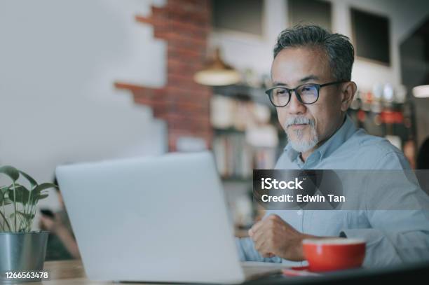 An Asian Chinese Senior Man Having Discussion With His Colleague Via Online Virtual Meeting In A Cafe Stock Photo - Download Image Now