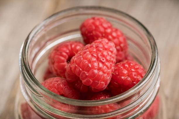 istock Ripe juicy raspberries in jar. Selective focus. 1266565748