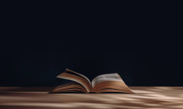 istock Reading and Education Learning Concept. Opened Book or Bible on Desk 1266565880