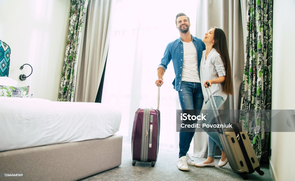 Young beautiful happy excited couple in love with suitcases in a modern hotel during vacation Hotel Stock Photo