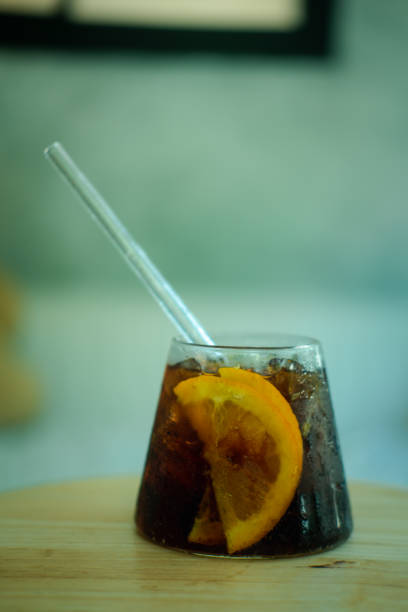 istock Cool soft drink with orange slices inside glass on wooden table 1266569330
