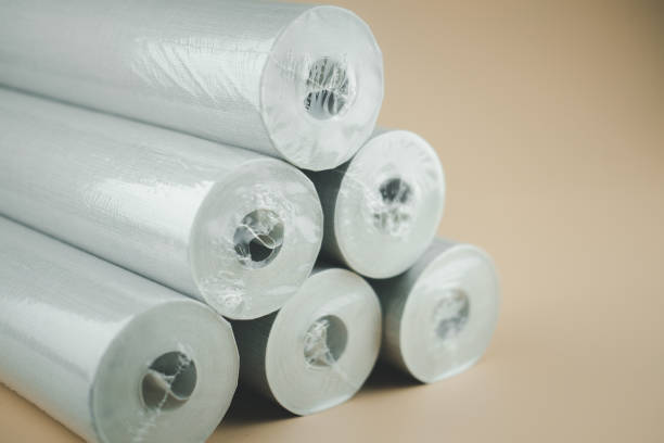 istock Wallpaper for decorating walls and repairs twisted into rolls in plastic packaging on orange background 1266569425