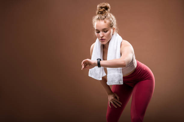 istock Tired young blond sportswoman in activewear looking at fitbit on her wrist 1266580507