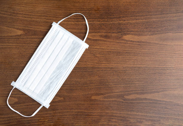 istock White surgical mask on old wooden background 1266581775