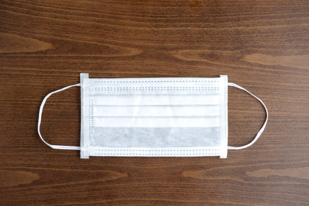 istock White surgical mask on old wooden background 1266581786