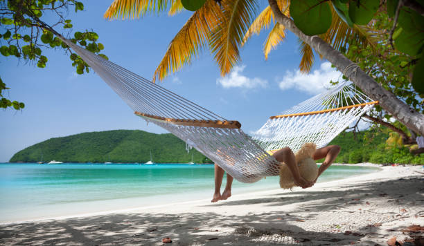 istock Woman relaxing in a hammock on a tropical beach 1266584257
