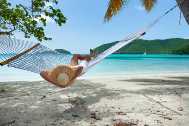 istock woman reading and relaxing in hammock on tropical beach 1266584258