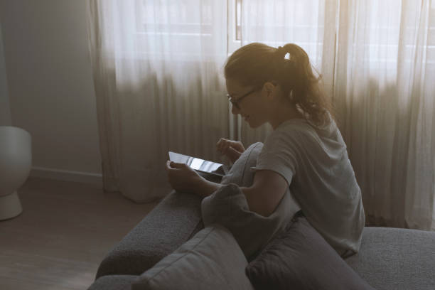 istock Woman relaxing on the sofa and connecting with her touch screen tablet 1266585285