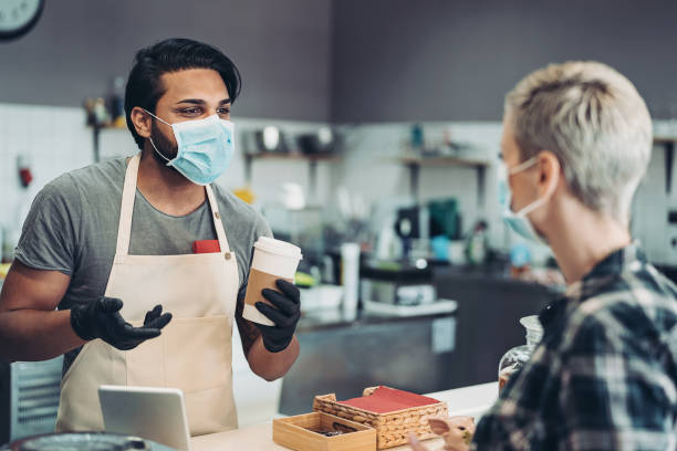 istock Cafe owner selling coffee wearing a face mask and protective gloves 1266587417