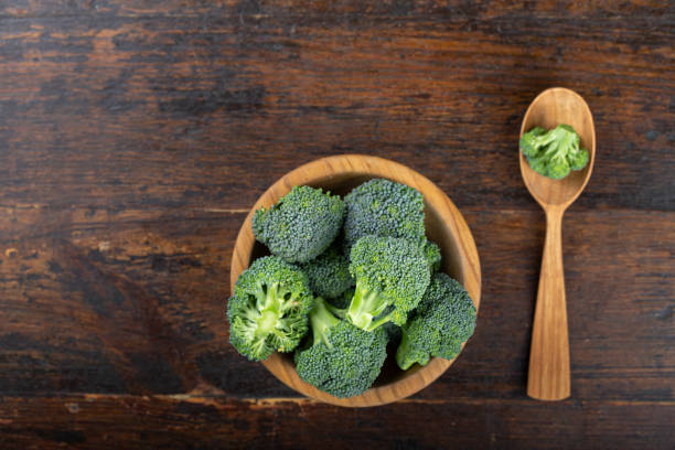 Fresh broccoli with in bowl on wooden table close up. Fresh broccoli with in bowl on wooden table close up. Fiber-rich food. broccoli crowns stock pictures, royalty-free photos & images