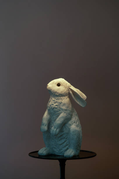 Ceramic hare for home interior decoration. White rabbit on black stand