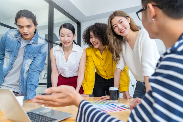 istock Multi ethnic group of successful creative business people using a laptop during candid meeting with successful result of profit from laptop 1266598421