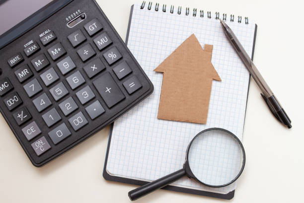 istock Cardboard house with notebook and pen. calculator on white table, business concept 1266598817