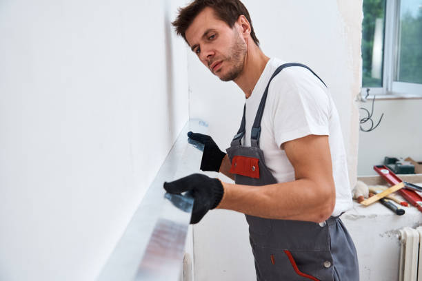 istock Renovation concept. Male worker plastering a wall using a long spatula 1266599567
