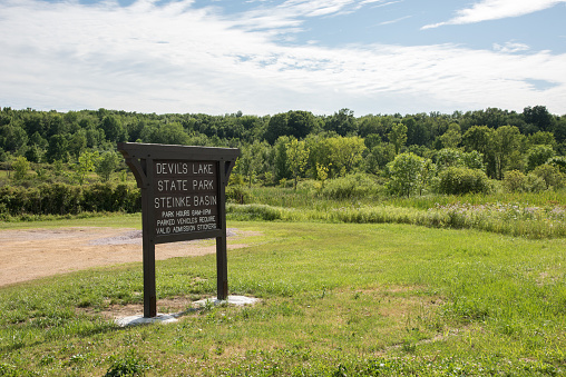 Baraboo, WI,United States-May 14,2014: Sign at the Devil's Lake State Park with native forest under a blue sky with clouds in Baraboo, Wisconsin