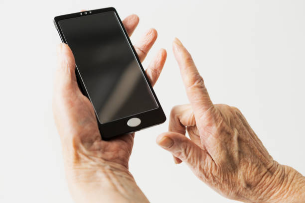 istock Wrinkled hands of an elderly woman using a modern smart phone 1266610116