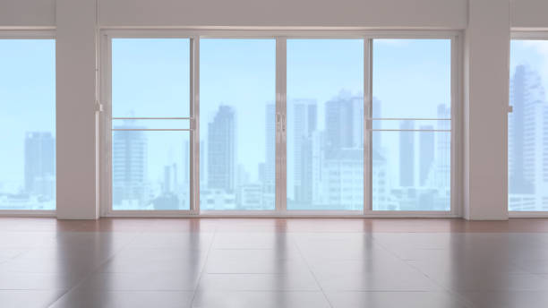 istock Inside view of glass sliding doors on tile floor in empty room with blurred cityscape view in blue sky background 1266618526