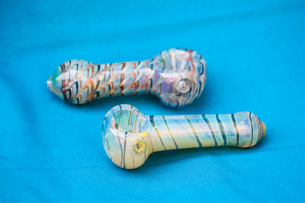 Pipe or bong for marijuana smoking Glass pipe or bong for marijuana smoking on a blue fabric background bong photos stock pictures, royalty-free photos & images