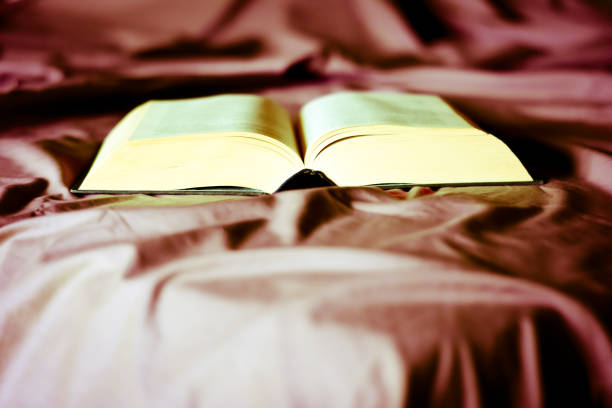 istock an open book on the sheets of the bed 1266622829