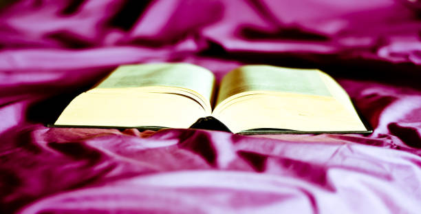 istock an open book on the purple unmade bed 1266622847