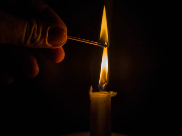 istock Matches burning to light a candle on black background 1266624777