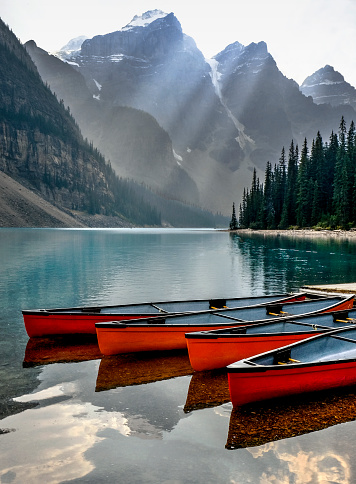 Calm evening waters reflect red canoes and the Valley of 10 Peaks in Moraine Lake, one of the most iconic and scenic locations in Canada.